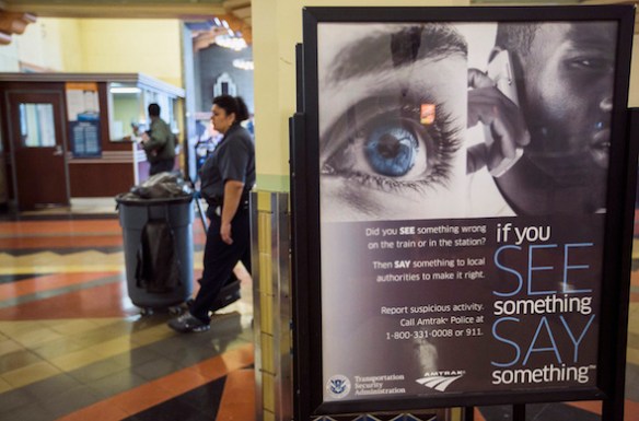 A janitor walks past Transportation Security Administration sign reading: "If you See Something Say Something," to encourage citizens to report suspicious activities at Union Station on Tuesday, April 16, 2013. The city increased security following bomb explosions in Boston that killed two people and injured more than 80 near the crowded finish line of the Boston Marathon. (AP Photo/Damian Dovarganes)